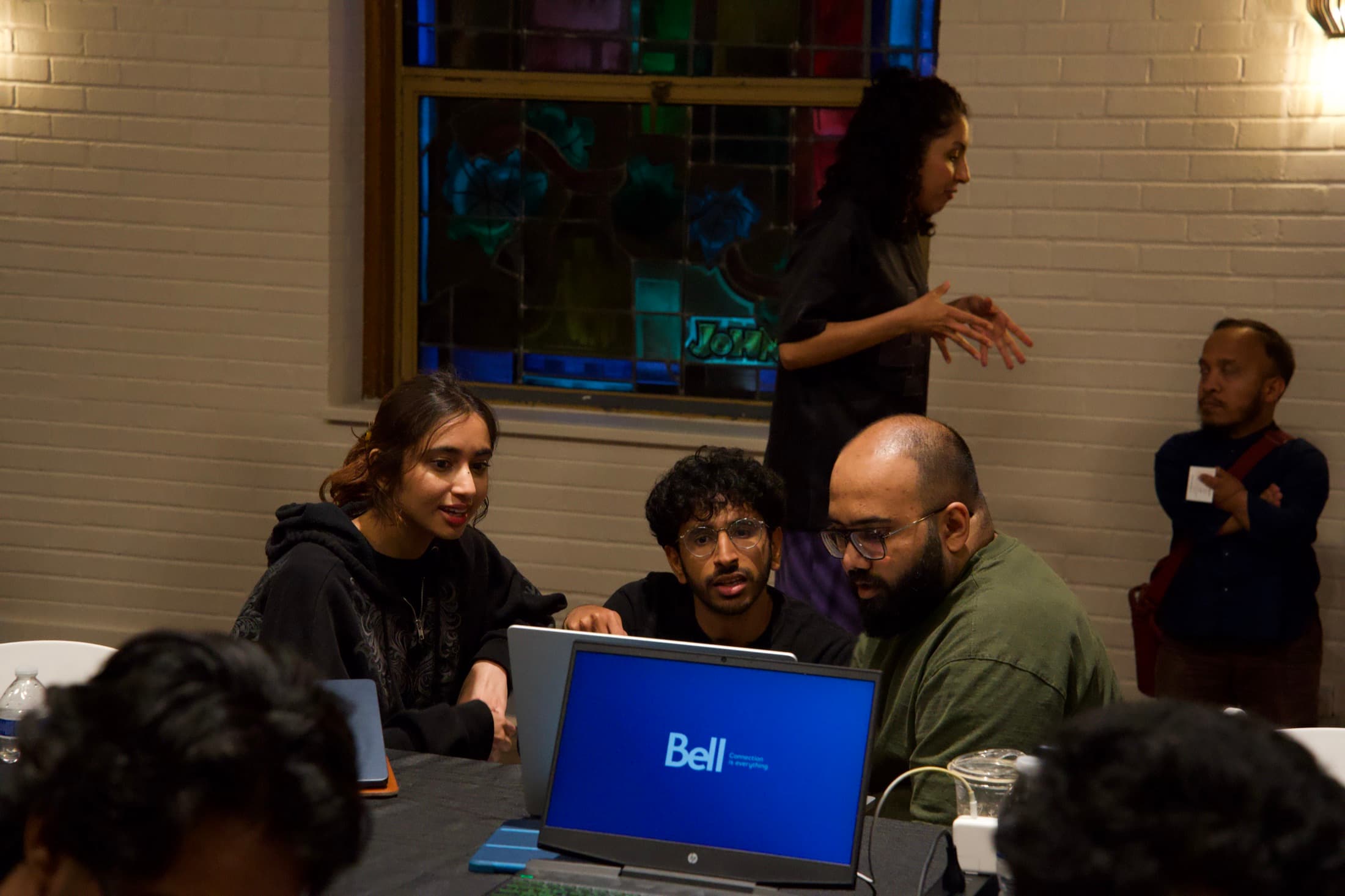 Three builders around a laptop, stained glass behind them