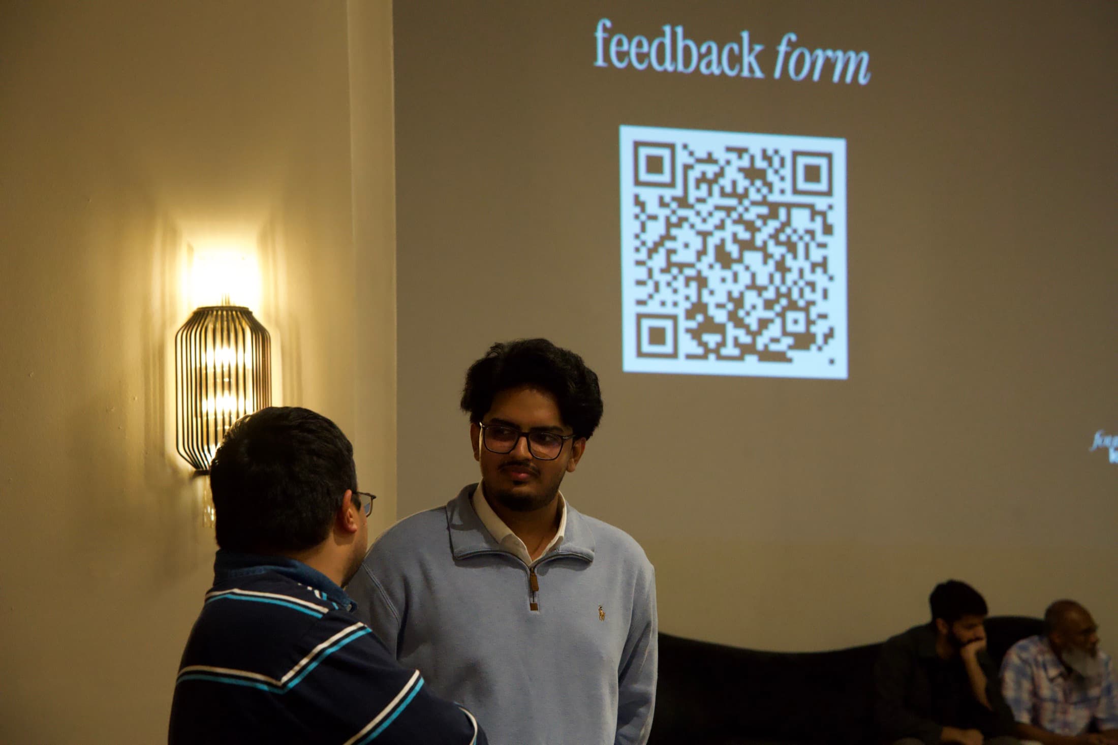 Two people talking under the feedback form on the big screen