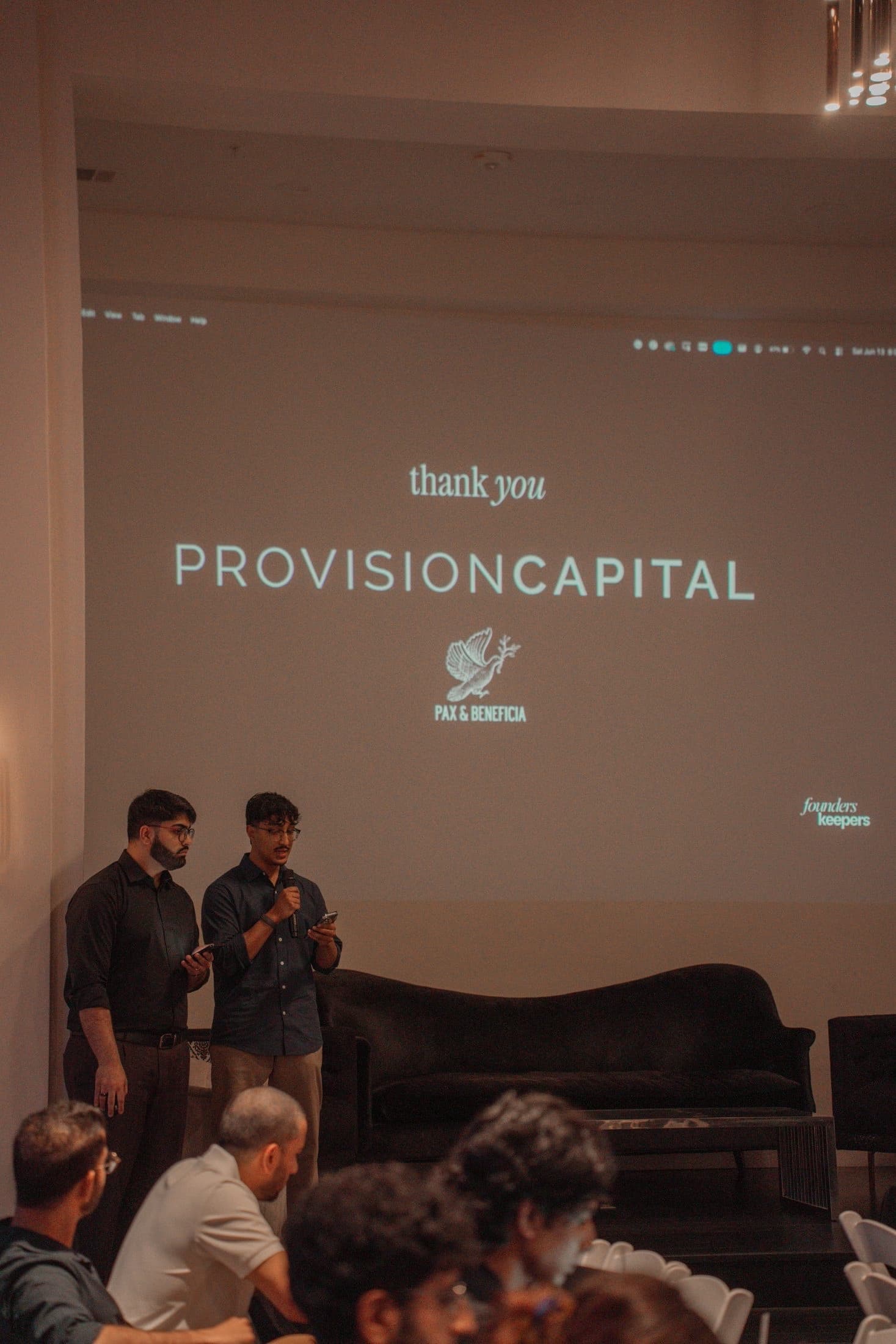 Two speakers on stage, the thank-you slide behind them